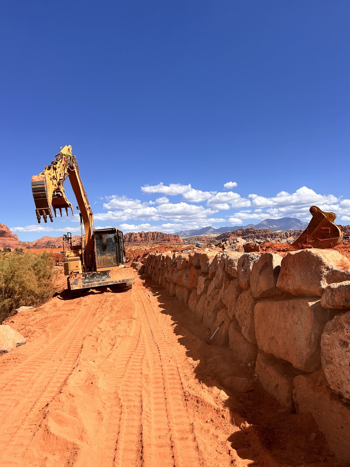 Massive boulder retaining wall built by Roxor South against Southern Utah red rock cliffs