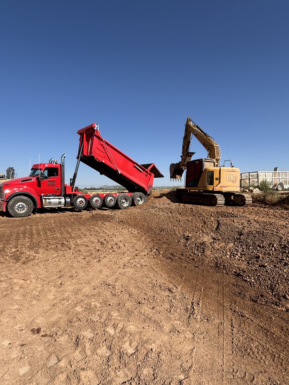 Roxor South red dump truck and CAT excavator on a La Verkin, Utah site with open Southern Utah sky overhead